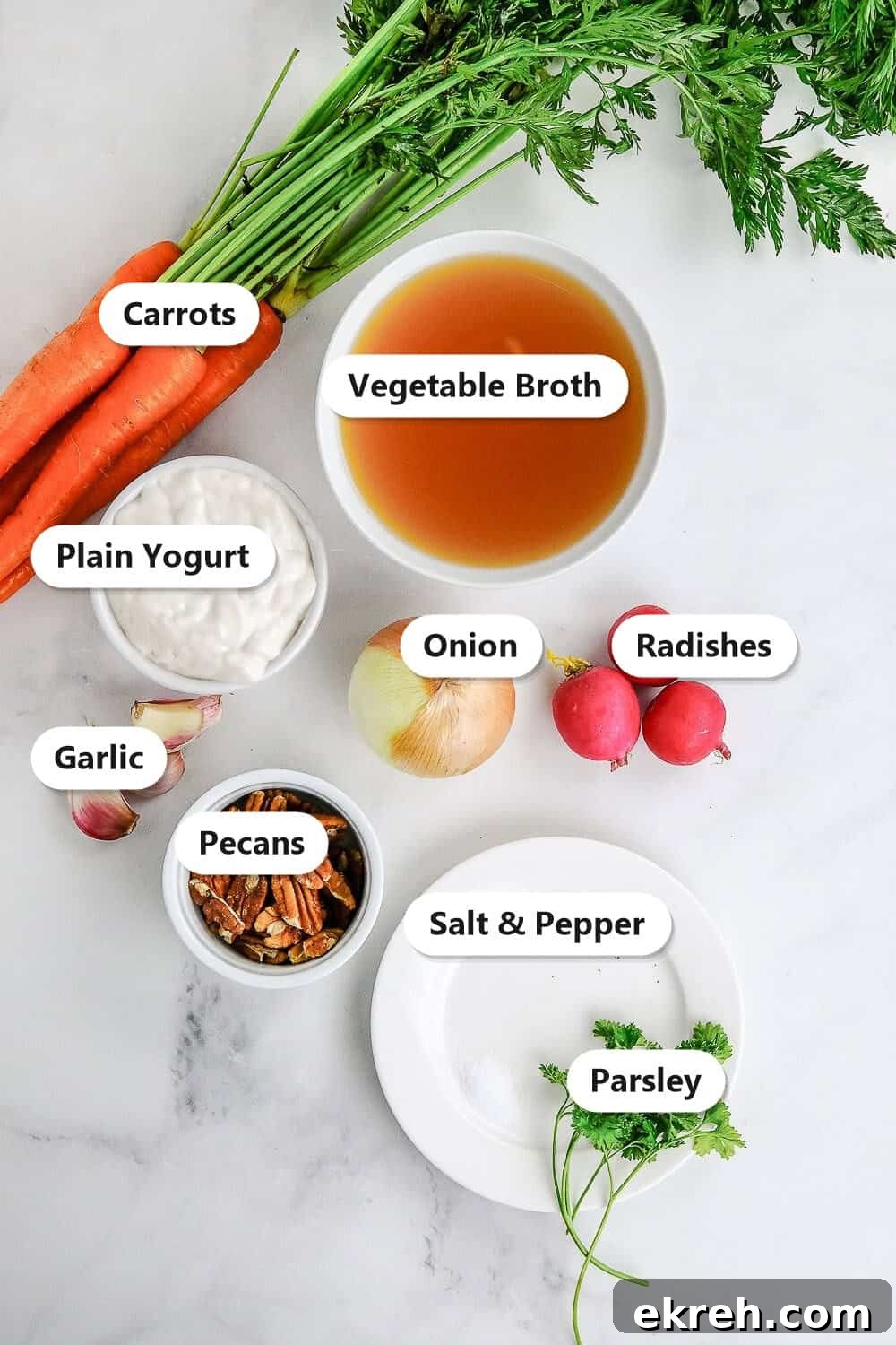 Labeled ingredients for creamy carrot soup including carrots, vegetable broth, plain yogurt, onion, radishes, garlic, pecans, and parsley.