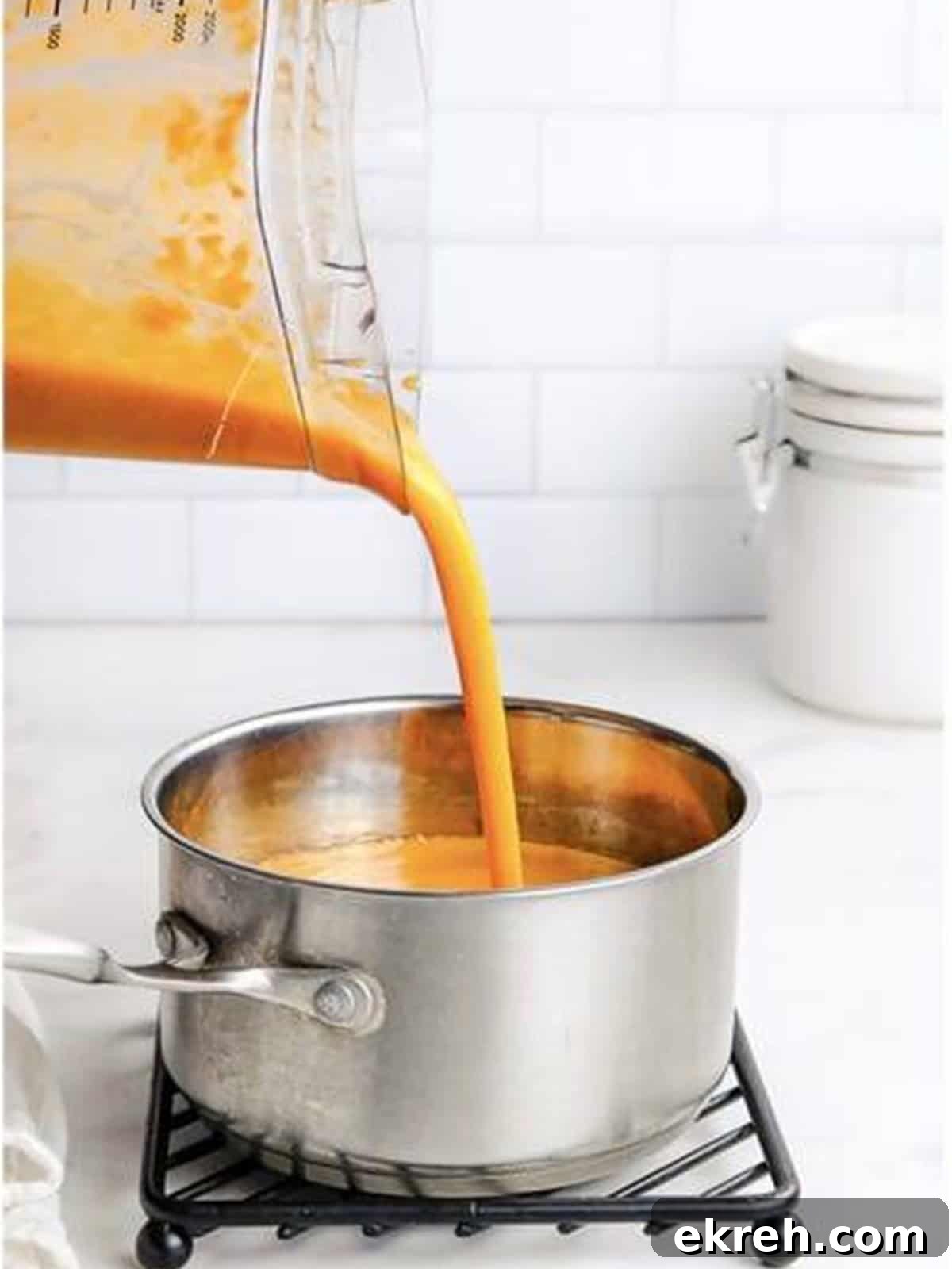 Blended carrot soup puree being poured back into a pot.
