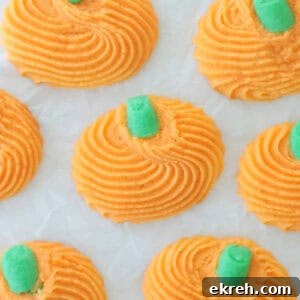 Piped pumpkin cookies with green stems.