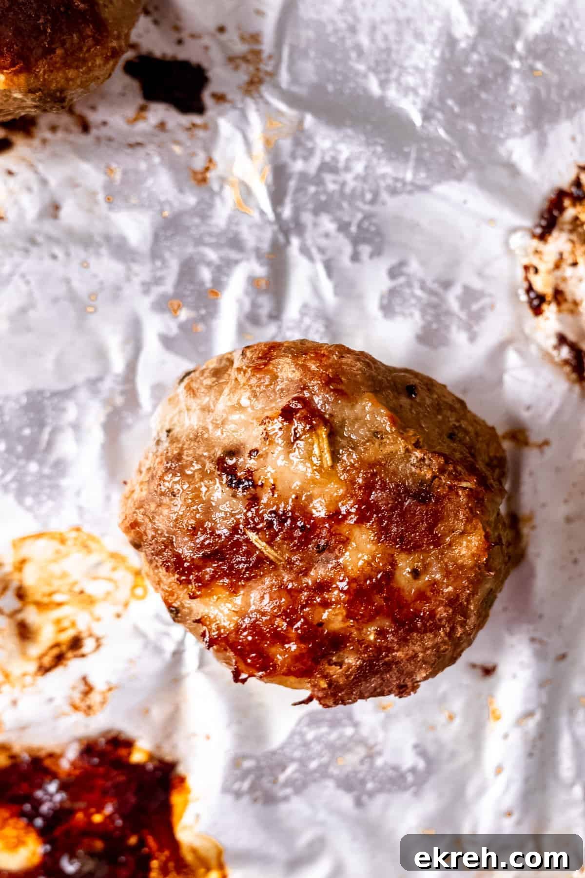 Classic Greek Chicken Meatballs with Tzatziki 4 Chicken meatballs on a baking tray with herbs.