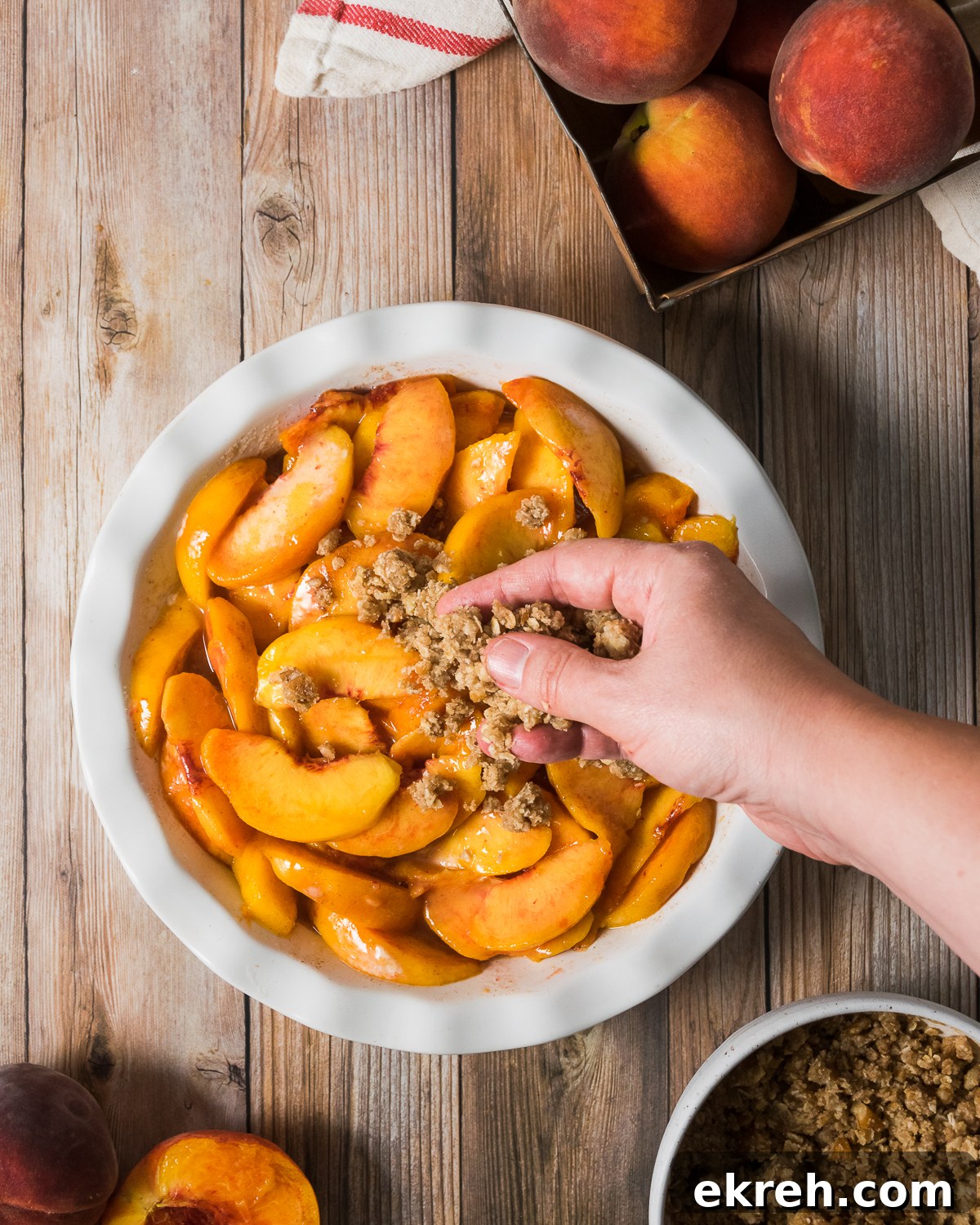 Oat topping being sprinkled over a peach crisp.