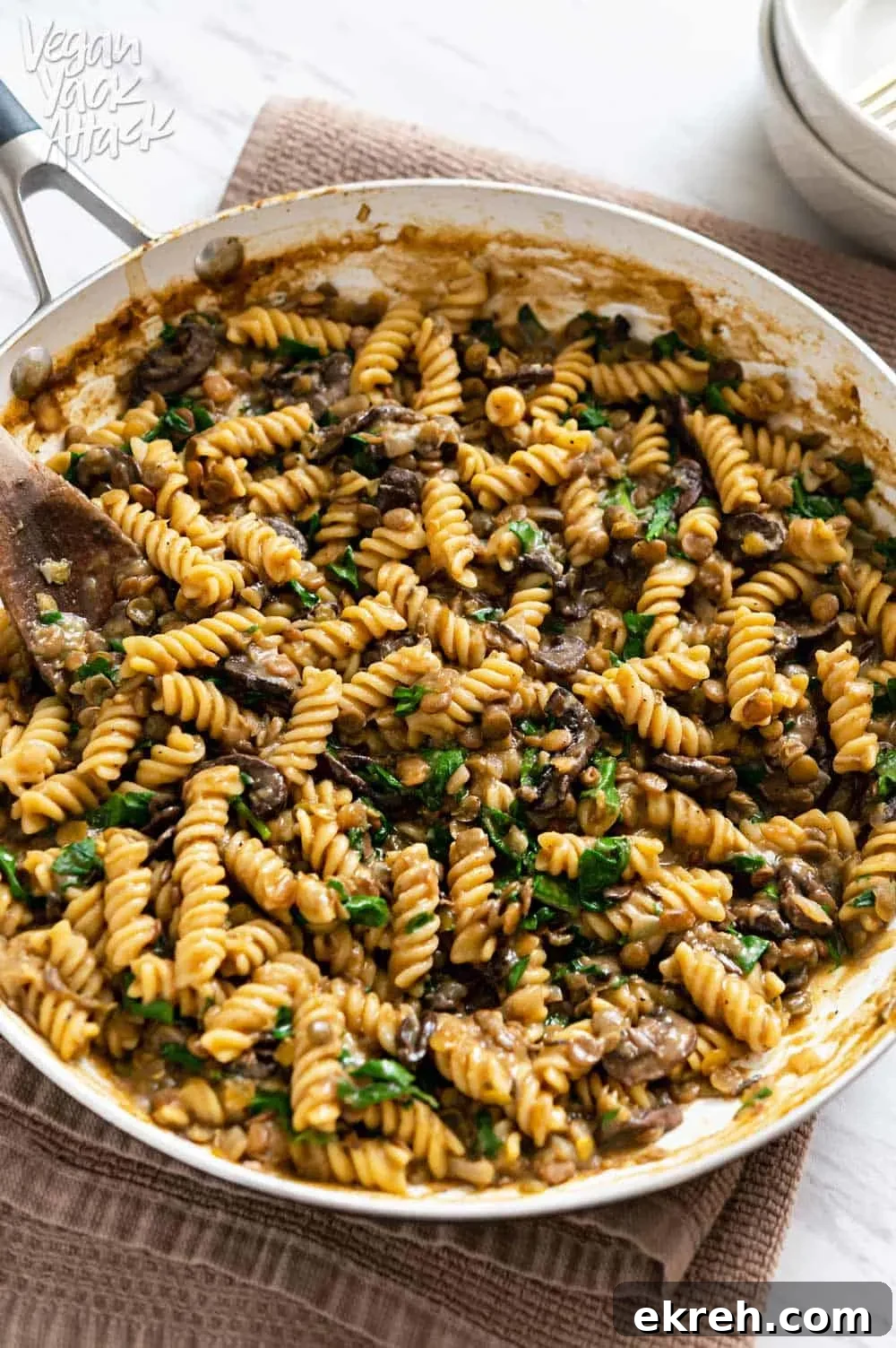 Image of a close-up of one-pot lentil mushroom pasta in a large pan sitting on a towel