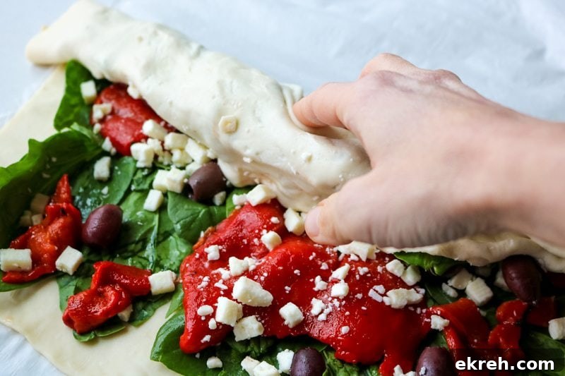 Showing rolling up the puff pastry into a log form.