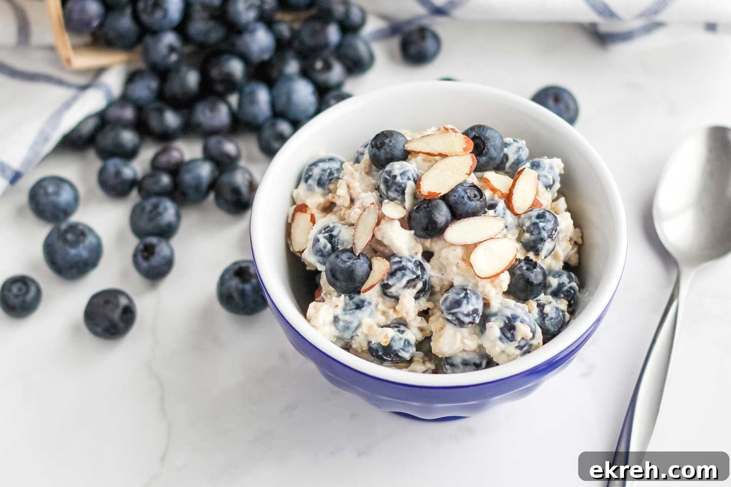 Easy Overnight Oats with Blueberries A little blue bowl of the finished blueberry overnight oats with extra blueberries and sliced almonds on top.