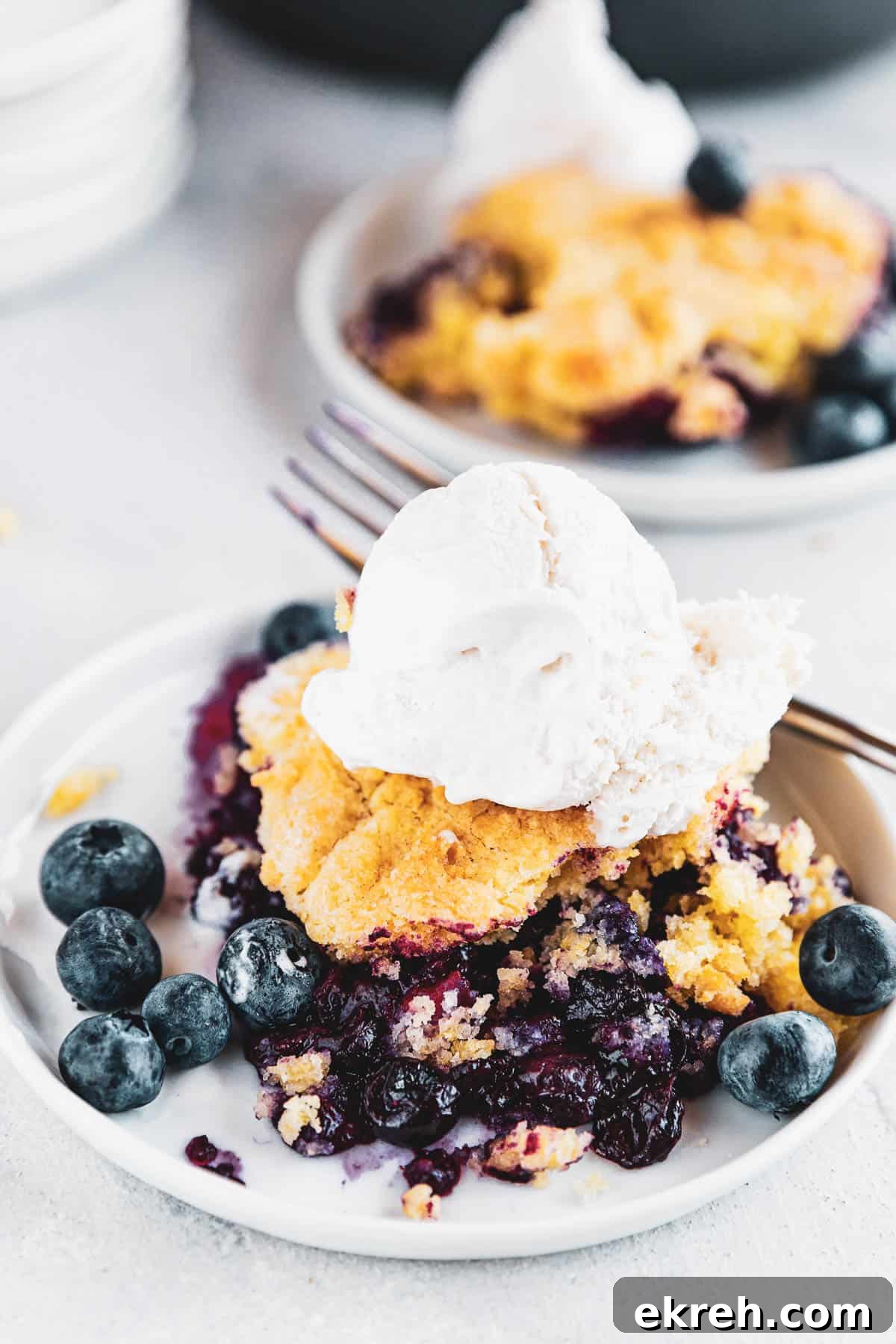 Blueberry Rhubarb Cobbler served on a plate and topped with ice cream scoop