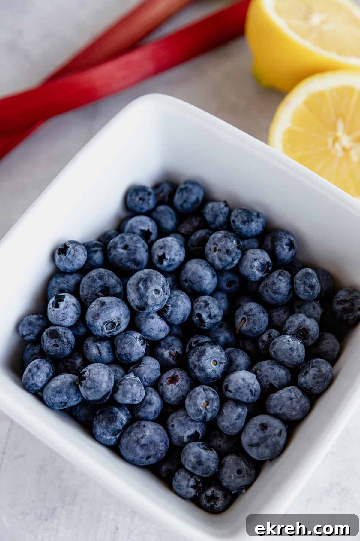A Bowl of Blueberries Beside Rhubarb and a Fresh Lemon Cut in Half