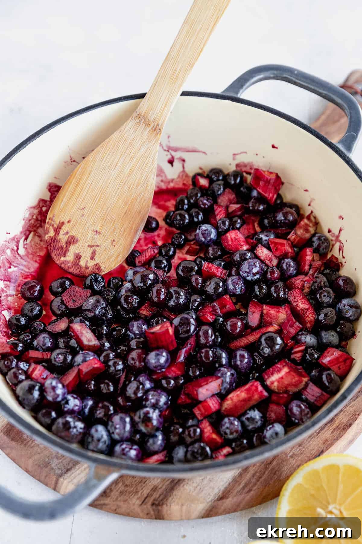The Filling for Blueberry Rhubarb Cobbler in a Skillet Being Mixed with a Wooden Spoon