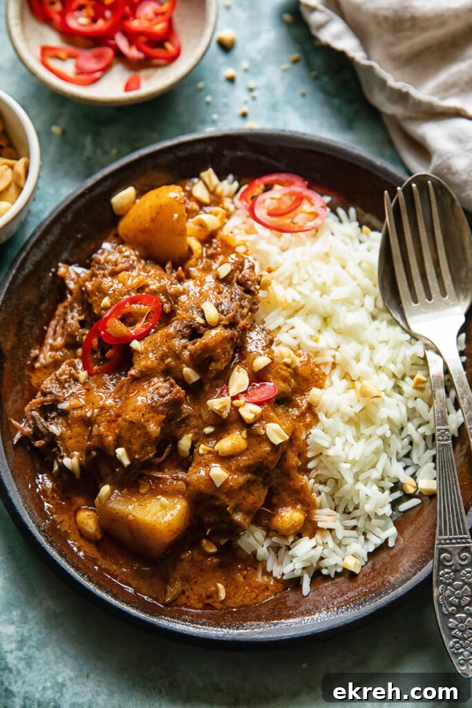 Slow-Braised Beef Short Ribs in Massaman Curry 6 Top down shot of massamman curry with short rib, potatoes and peanuts on a plate with rice and a fork