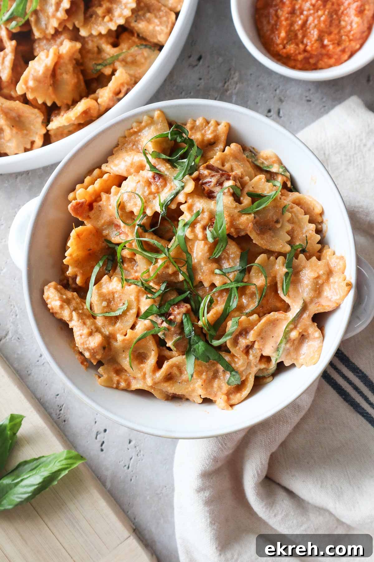 white bowl with chicken ricotta pasta topped with fresh basil.