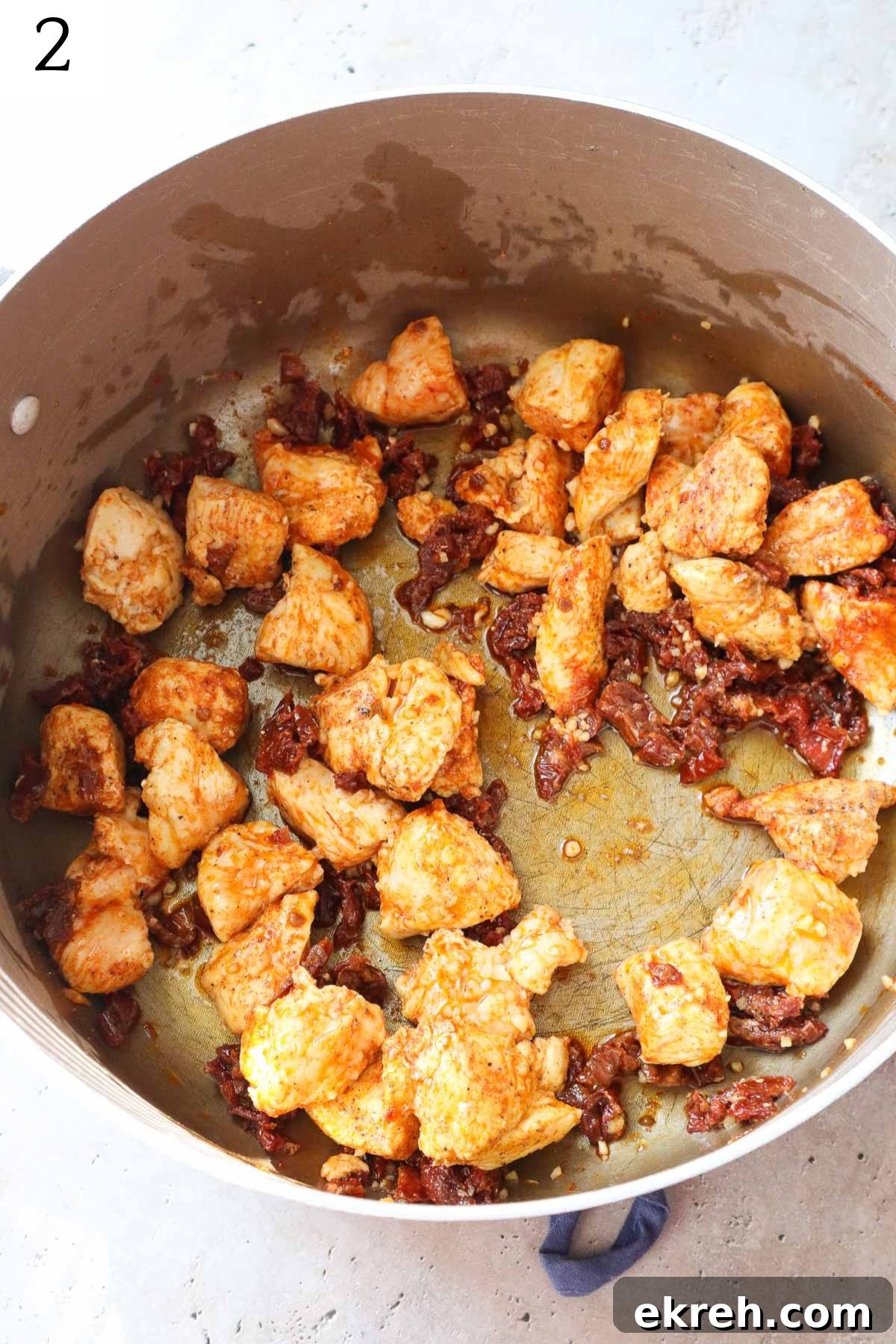 pot with sauteed chicken, seasonings, and sundried tomatoes.