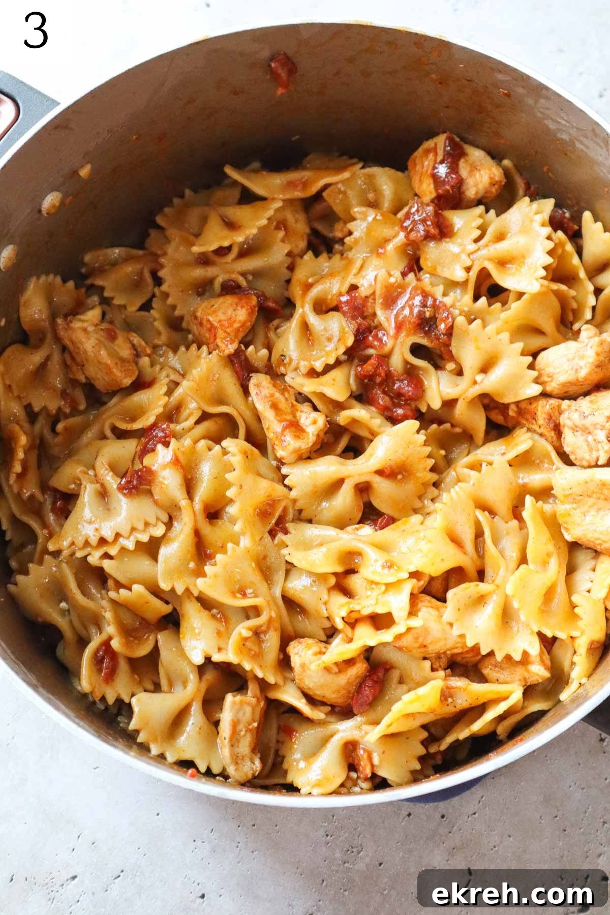 pot with pasta, chicken, and tomatoes cooked down.