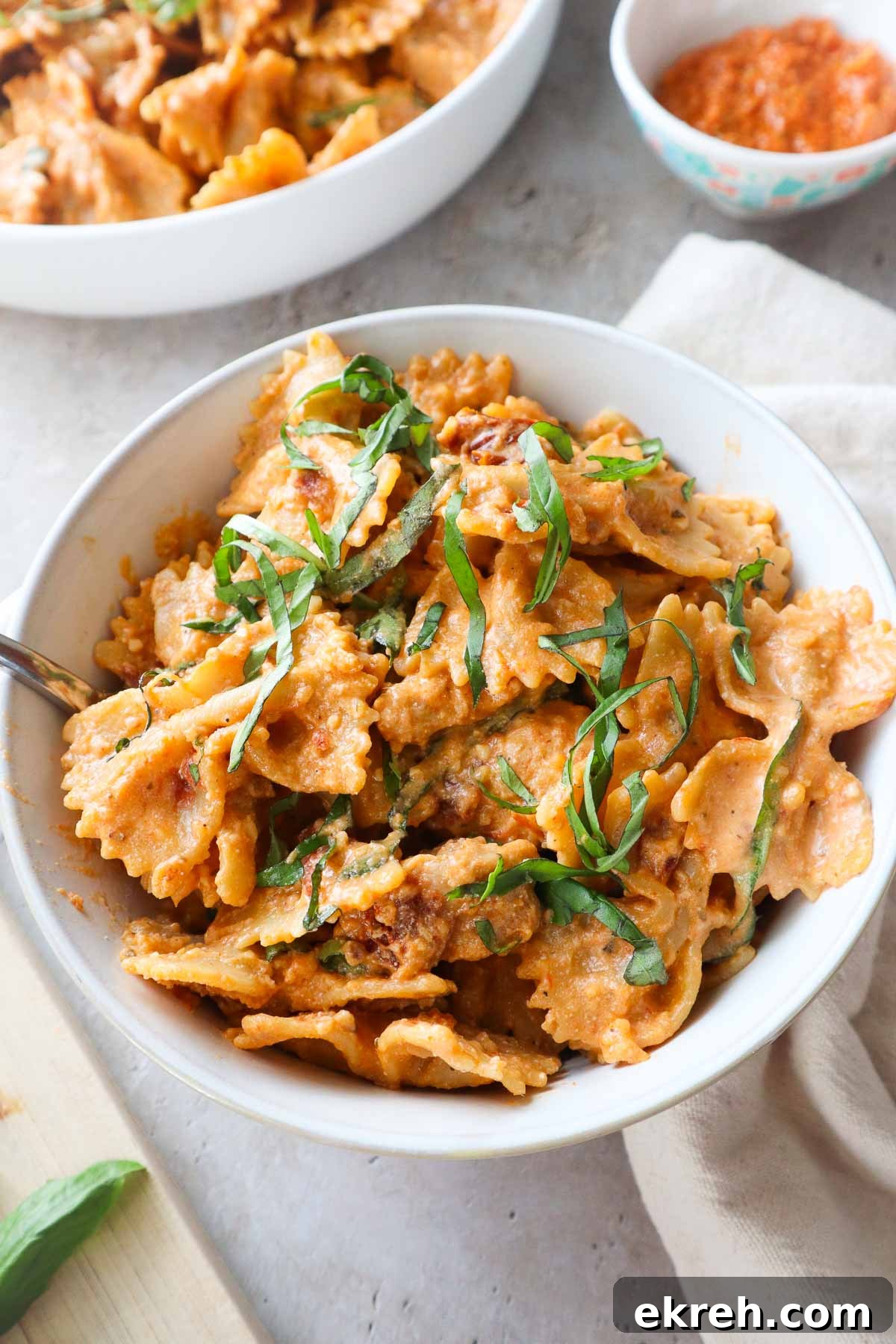white bowl with chicken ricotta pasta topped with fresh basil.