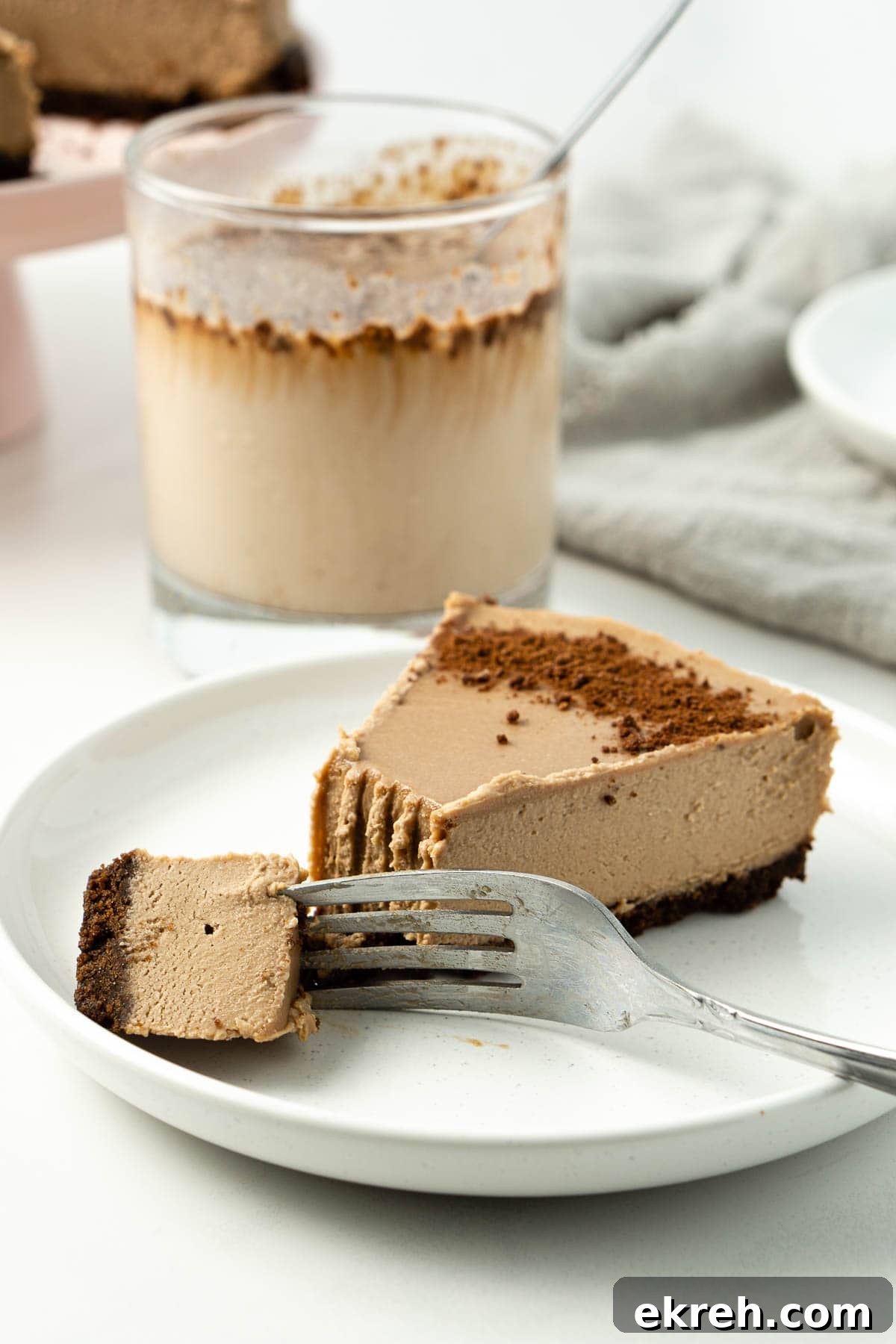 Creamy No-Bake Vegan Milo Cheesecake Recipe 8 Slice of Milo cheesecake on a white plate with a fork and bite taken.