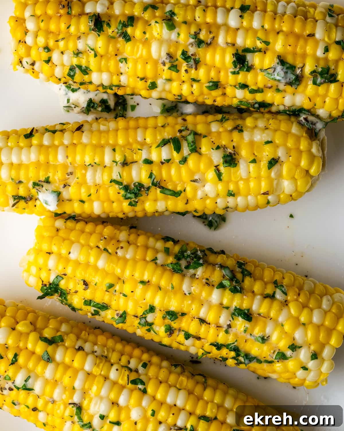 Top view of corn on the cob coated with butter and herbs.