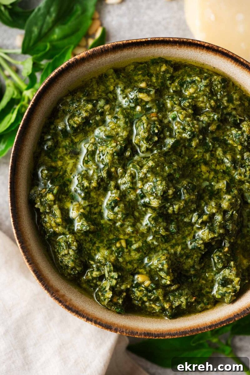 A close-up of food processor basil pesto in a bowl showing a vibrant green colour and creamy consistency.
