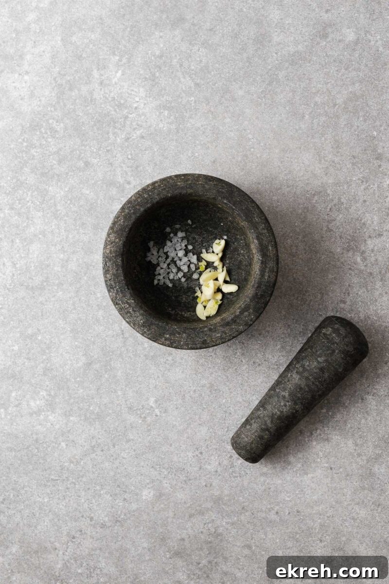 Roughly chopped garlic with coarse sea salt in a mortar.