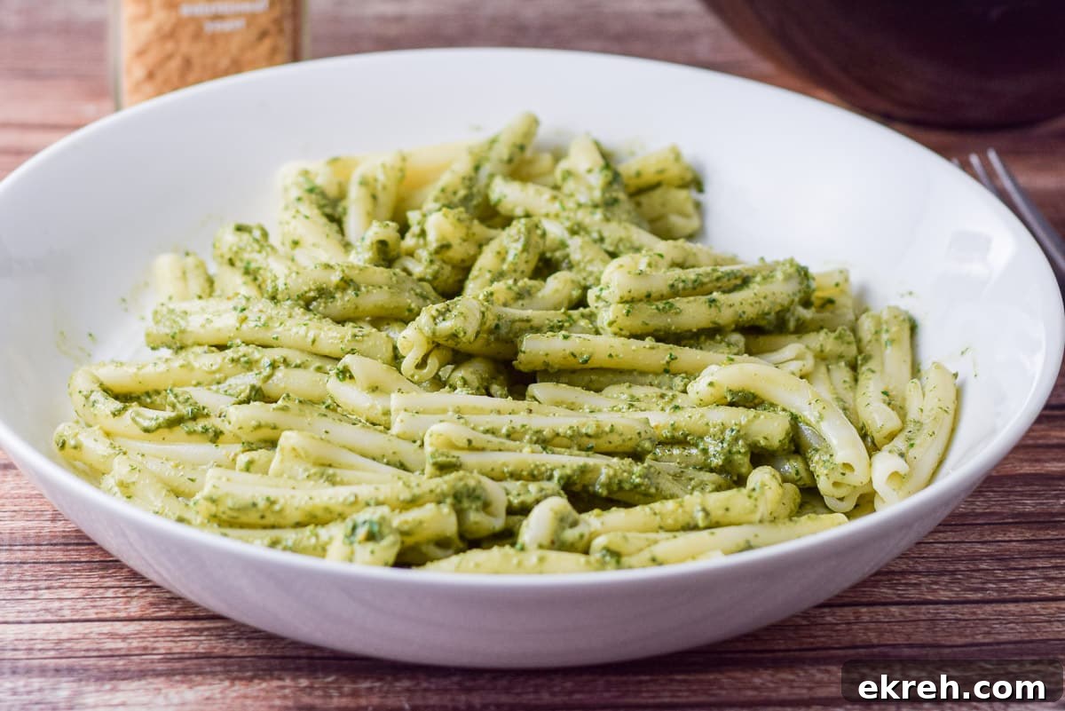 horizontal photo of a white deep dish filled with pasta and pesto