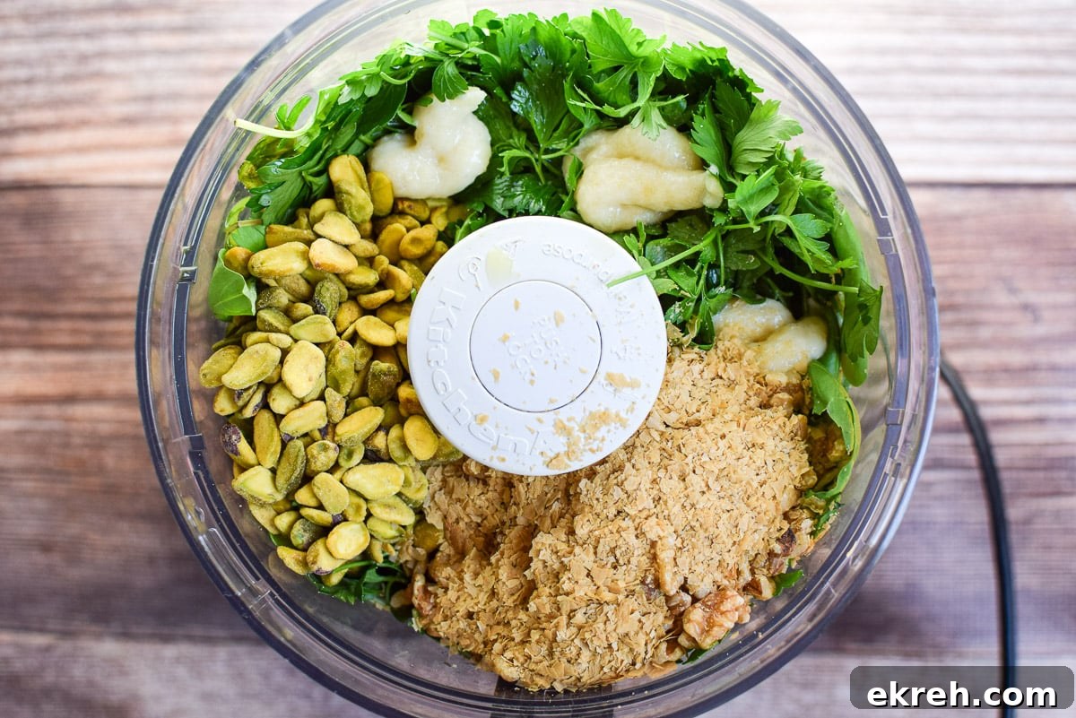 Overhead view of the food processor container with the ingredients for the pesto in it