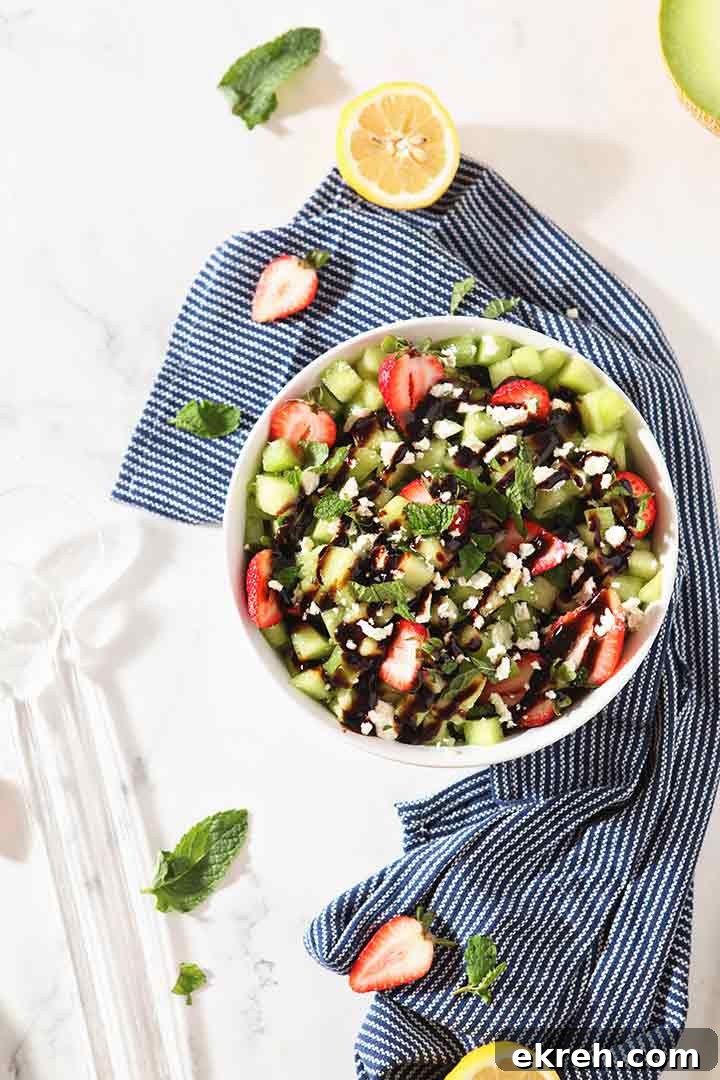 Overhead image of the final Strawberry Melon Salad in a white bowl with a blue napkin