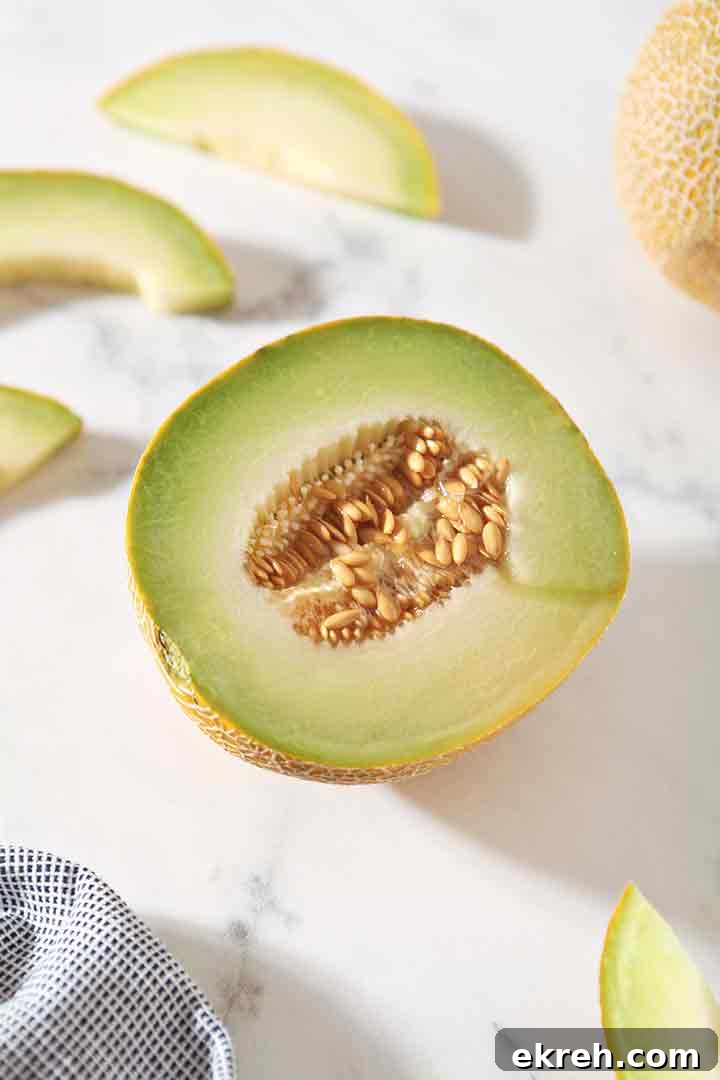 A halved Galia melon is shown on a marble backdrop