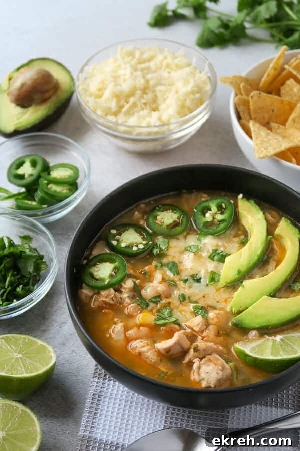 instant pot white chicken chili (dairy-free) shown with toppings: jalapeño, avocado, cilantro, Monterey jack cheese, and limes