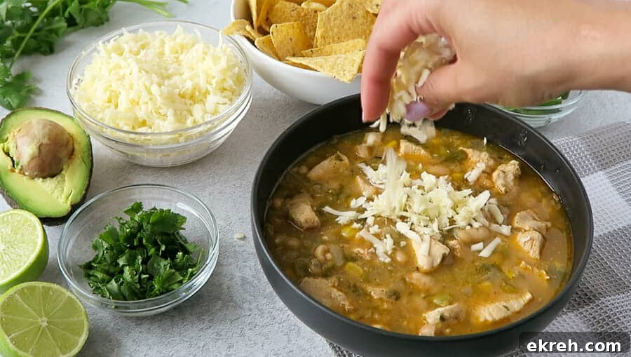 monterey jack cheese being sprinkled on a bowl of Instant Pot White Chicken Chili (Dairy-free)