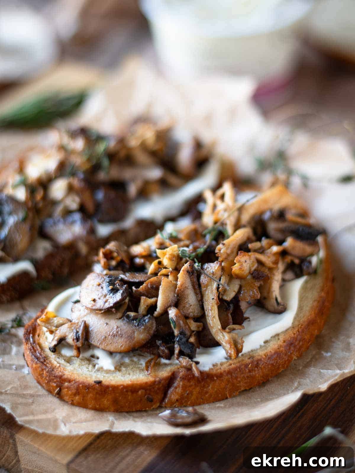 Angled view of 2 slices of mushroom tartine on parchment paper.