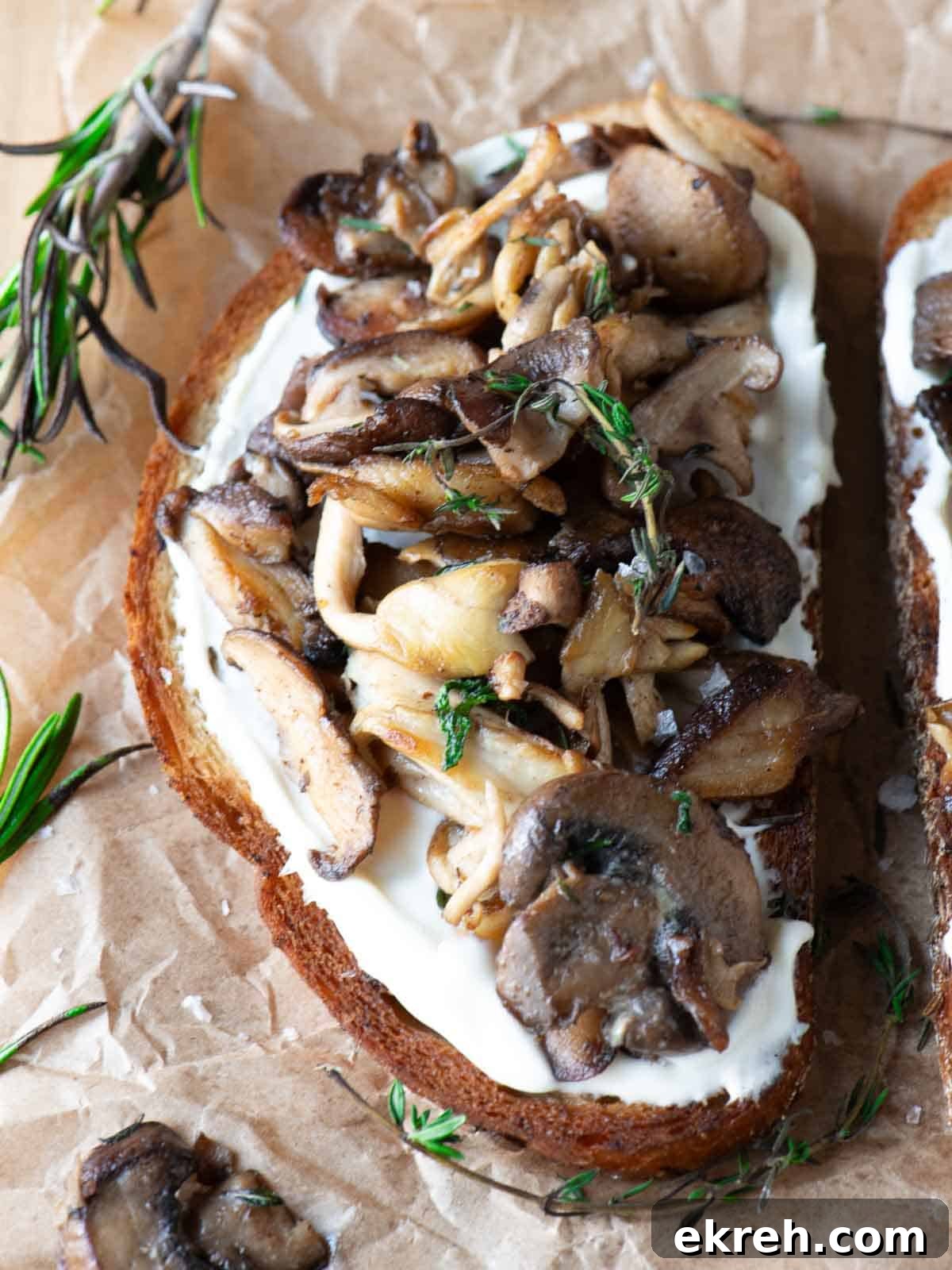 Close-up of mushroom toast with rosemary and thyme on top.