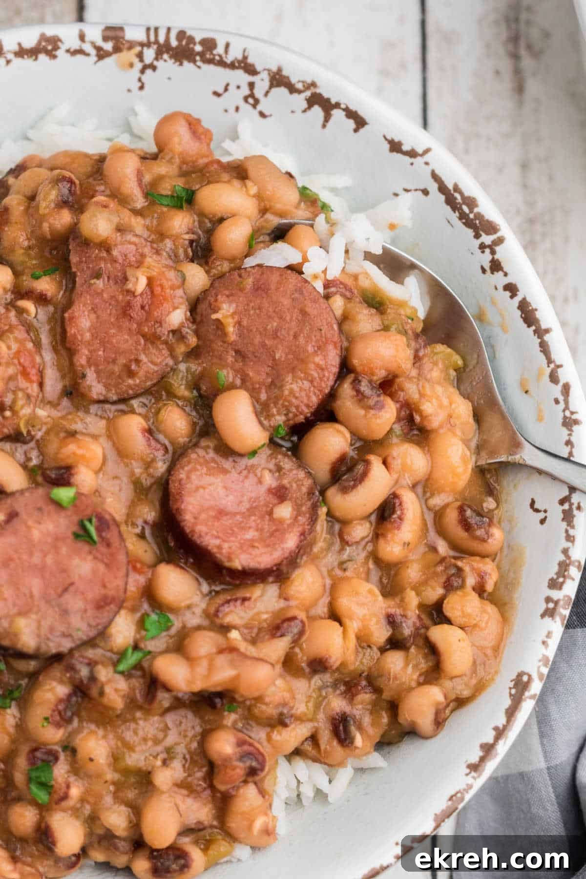 Close up shot cropped square, of a crock pot hoppin john with a spoon diggin in.