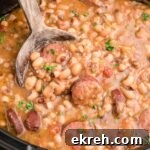 Close up shot cropped square, of a crock pot hoppin john with a spoon diggin in.
