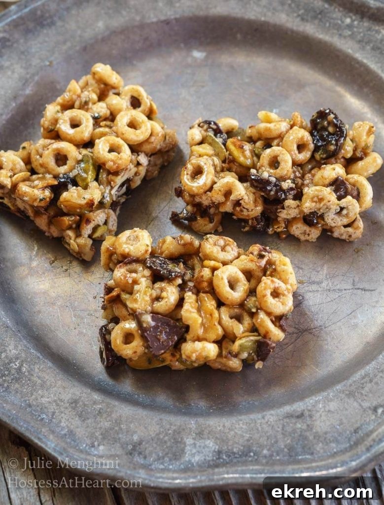 Three bars made from honey, whole-grain cereal, and chocolate chunks sitting on a metal plate