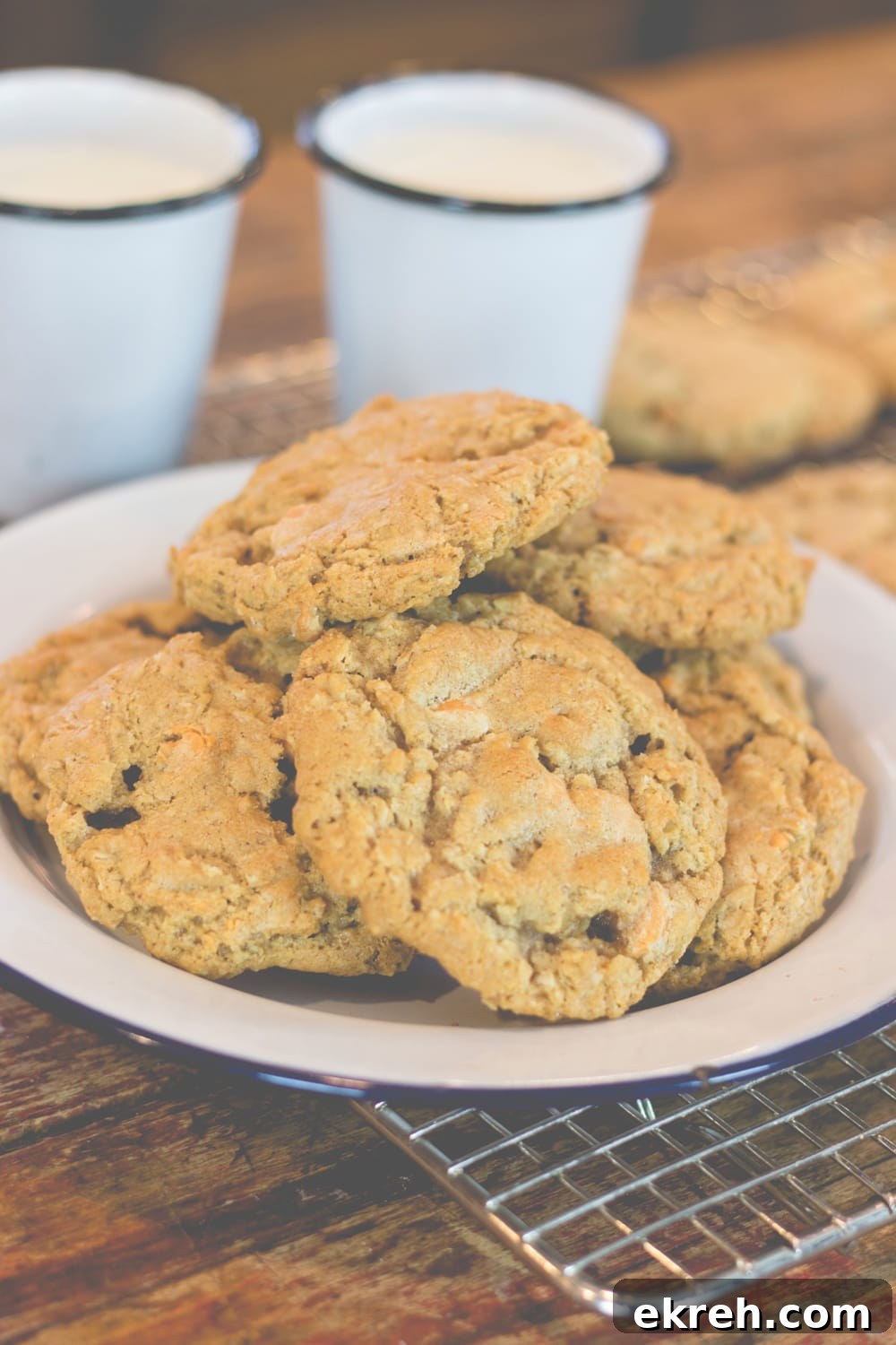 Chewy Brown Butter Oatmeal Cookies Recipe 4 A stack of cookies sits on a plate with glasses of milk behind.