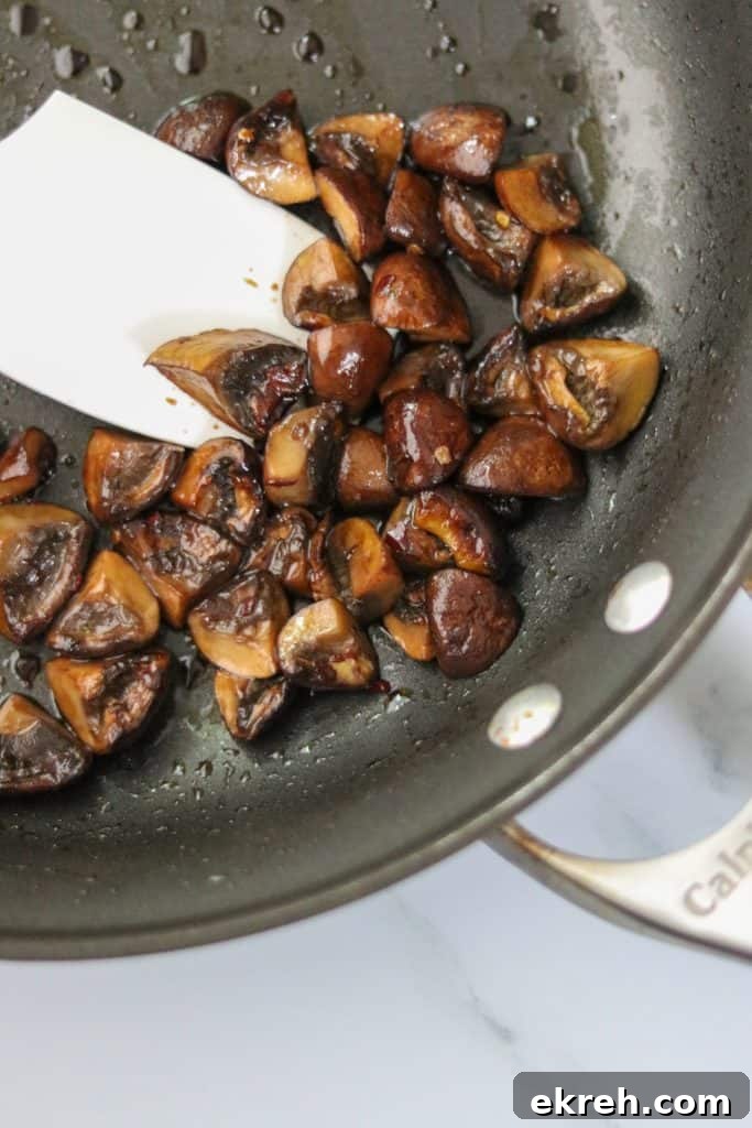 Balsamic-Glazed Mushroom Smorrebrod with White Bean Puree 6 Mushrooms cooking in a pan with a spatula