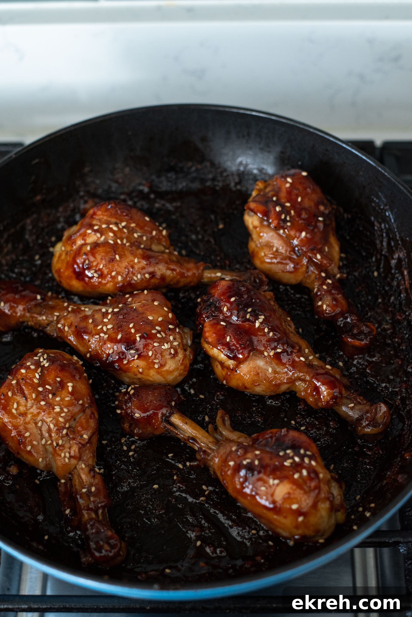 Coating chicken drumsticks with sticky, glossy teriyaki glaze.