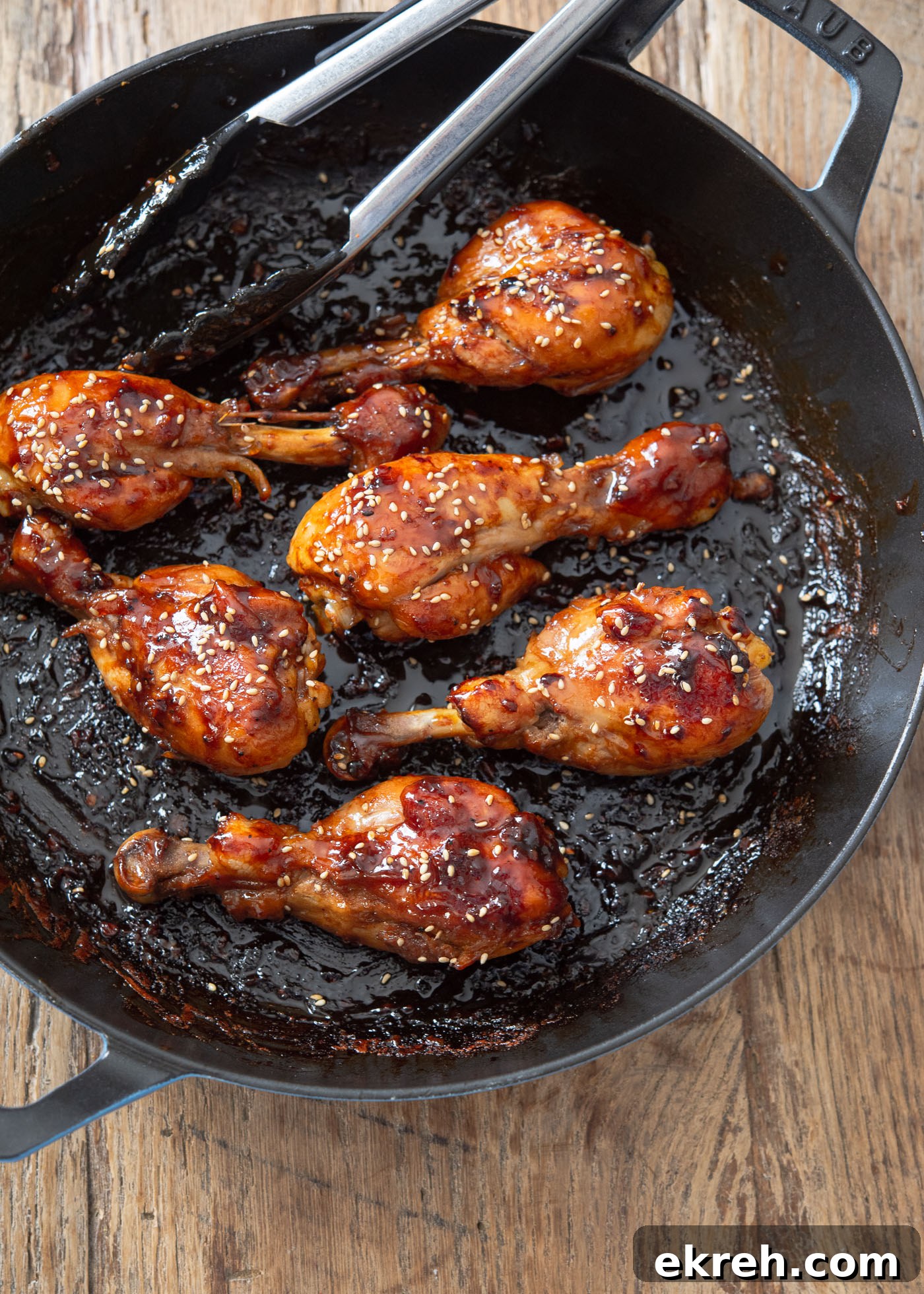 Quick teriyaki sauce glazed chicken drumsticks in a skillet.