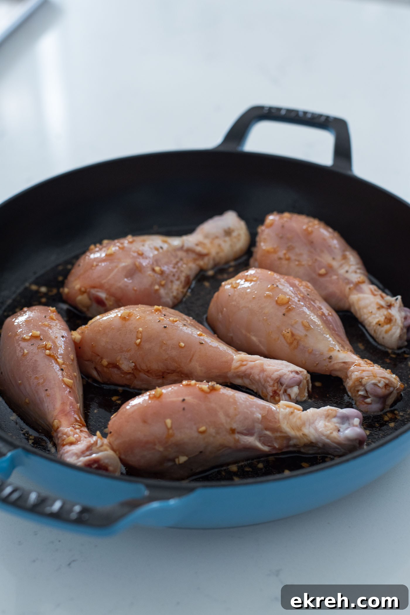 Skillet chicken drumsticks cooking in homemade teriyaki sauce.
